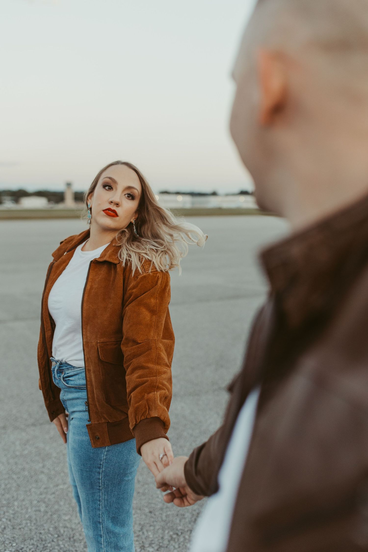 A playful moment captured between two people on an airport tarmac with an aircraft in background.