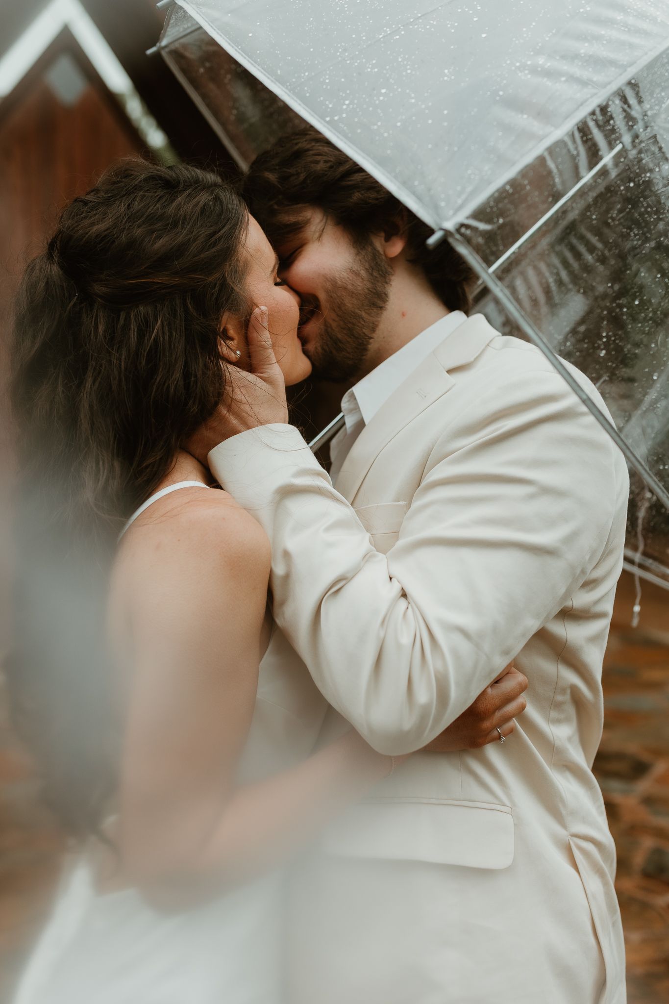 A romantic moment shared under a clear umbrella on a misty day.