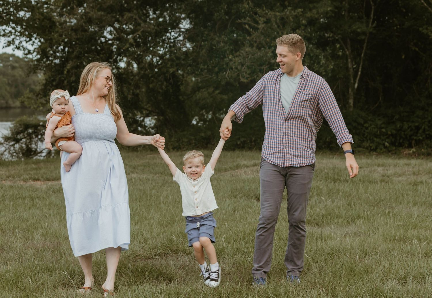 A candid family walking shot in a grassy field during golden hour.