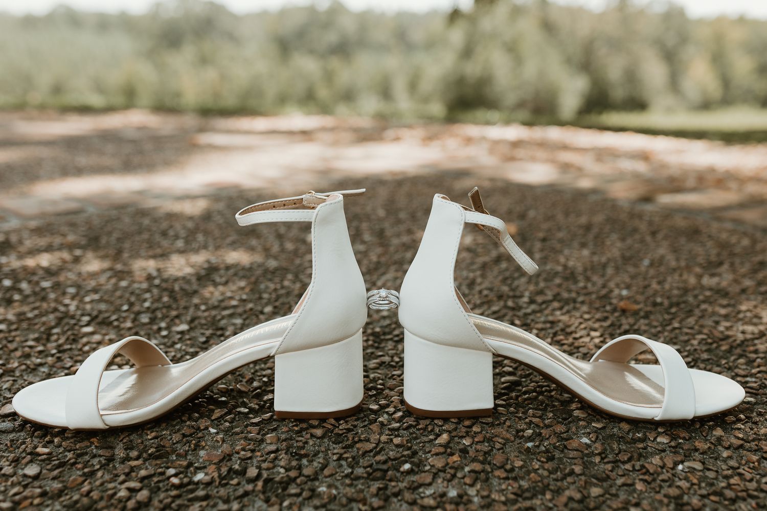 White platform wedding shoes arranged on a gravel path in natural lighting.