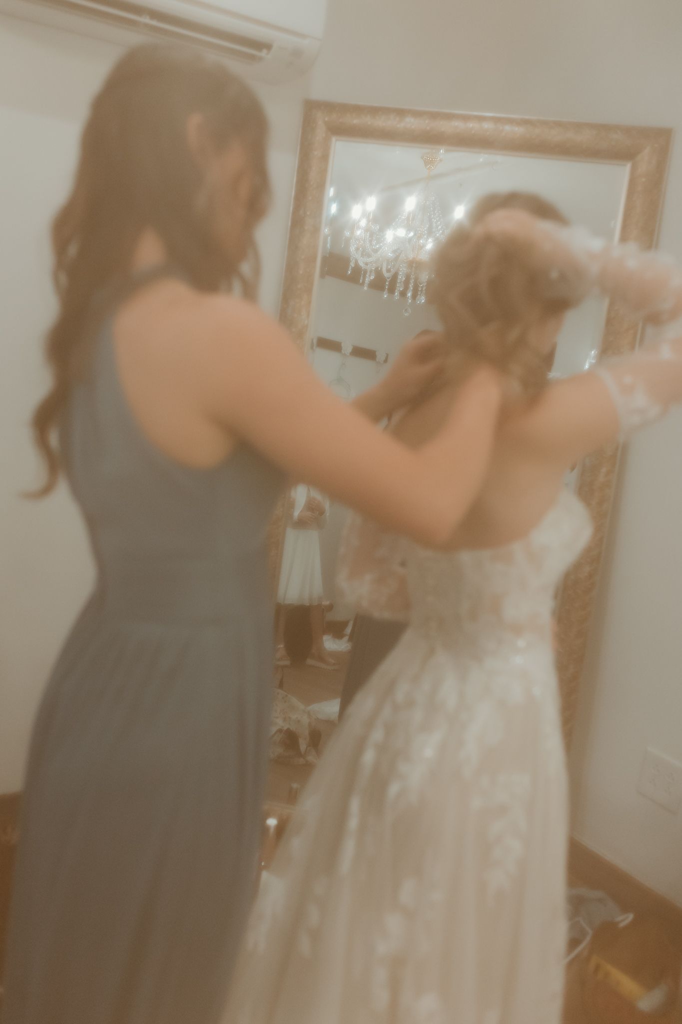 Wedding dress fitting scene with attendants helping adjust the gown.