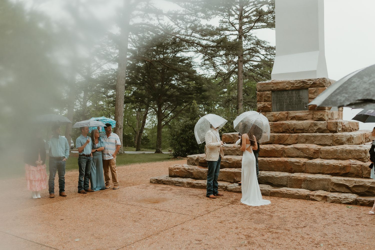 A romantic outdoor ceremony setup with stone steps leading to a white cross against a misty mountain backdrop.
