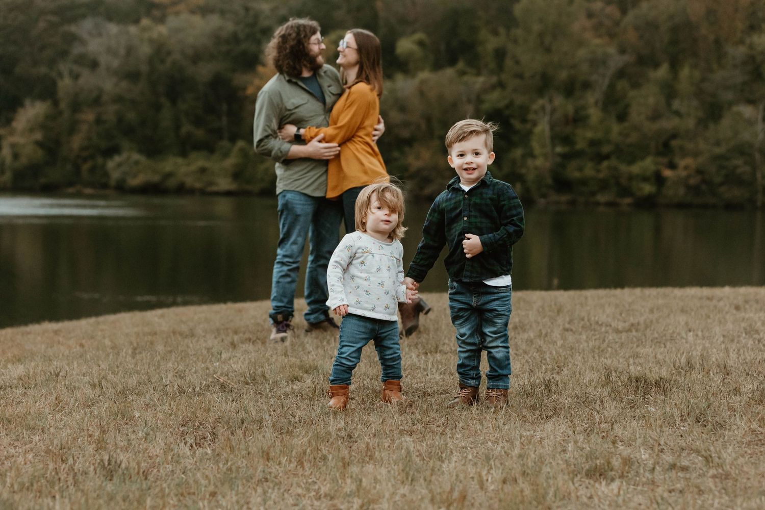 Family walking together across a grassy hillside during golden hour.