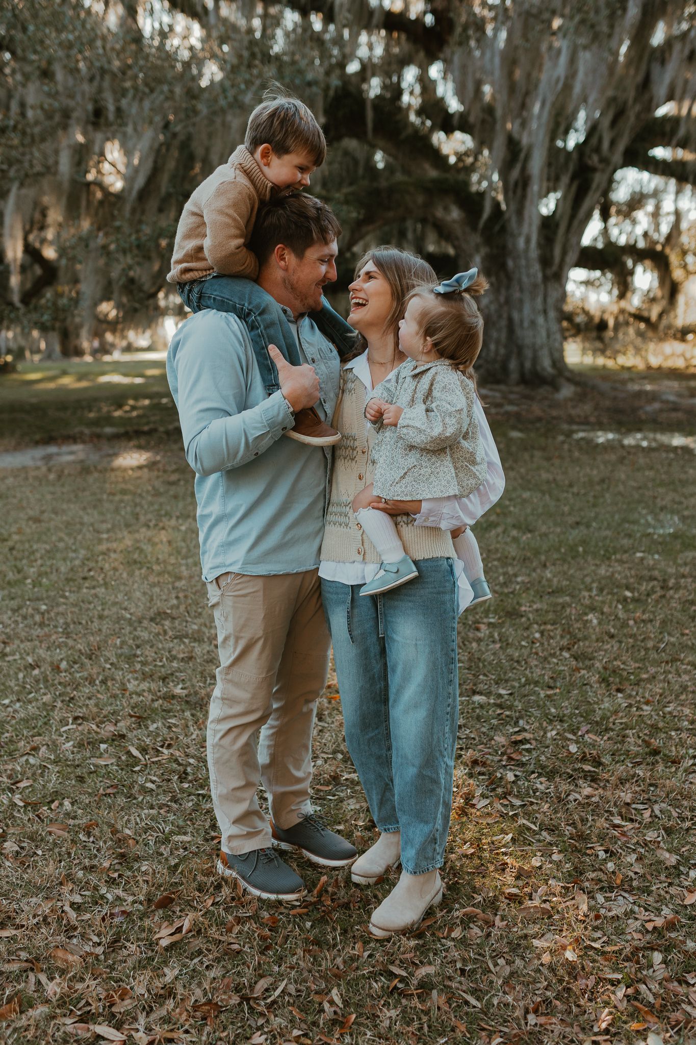 Family sharing playful moments together on fallen autumn leaves.