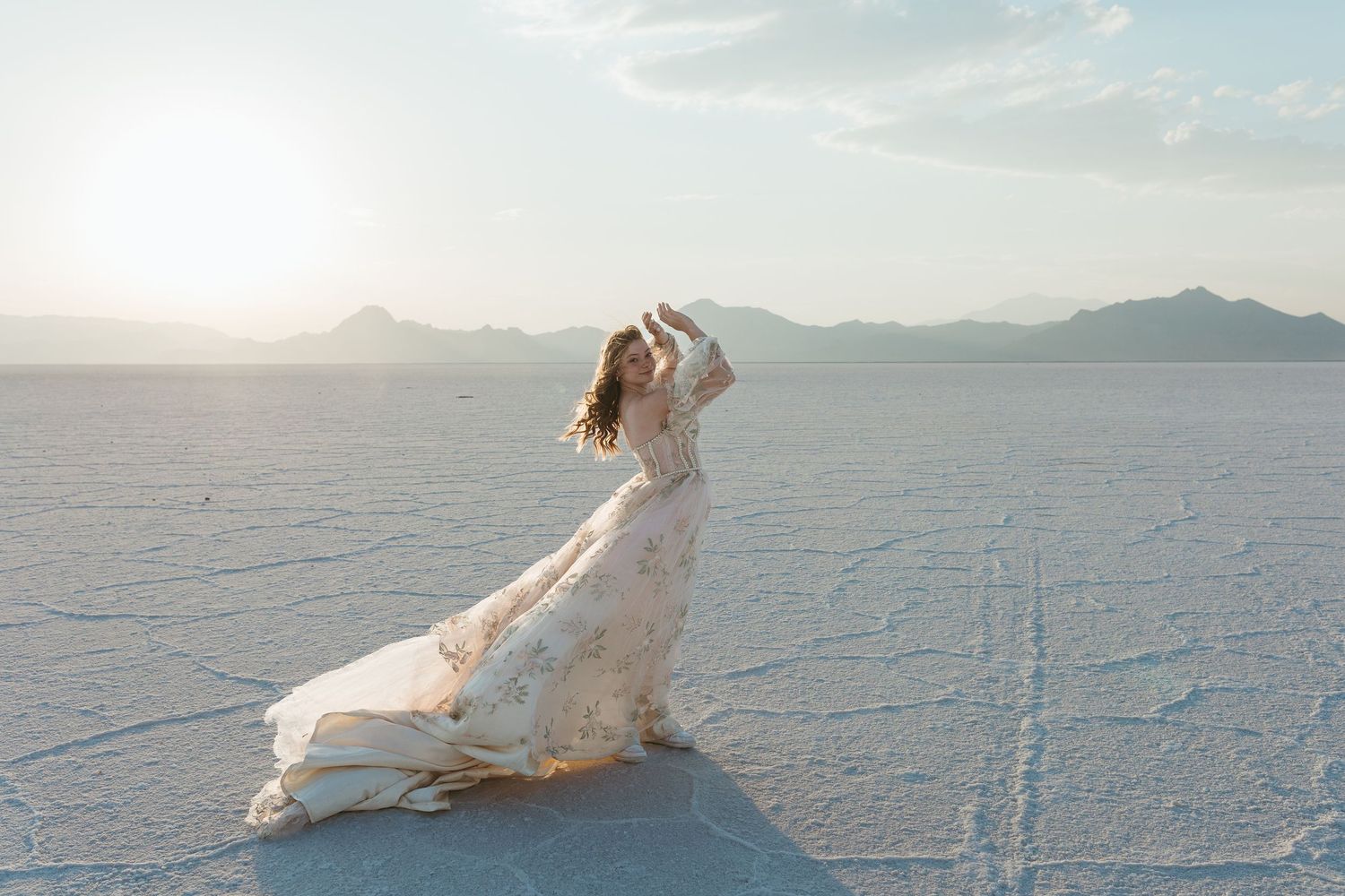 Artistic flowing dress photos on salt flats at sunset with mountains in background.