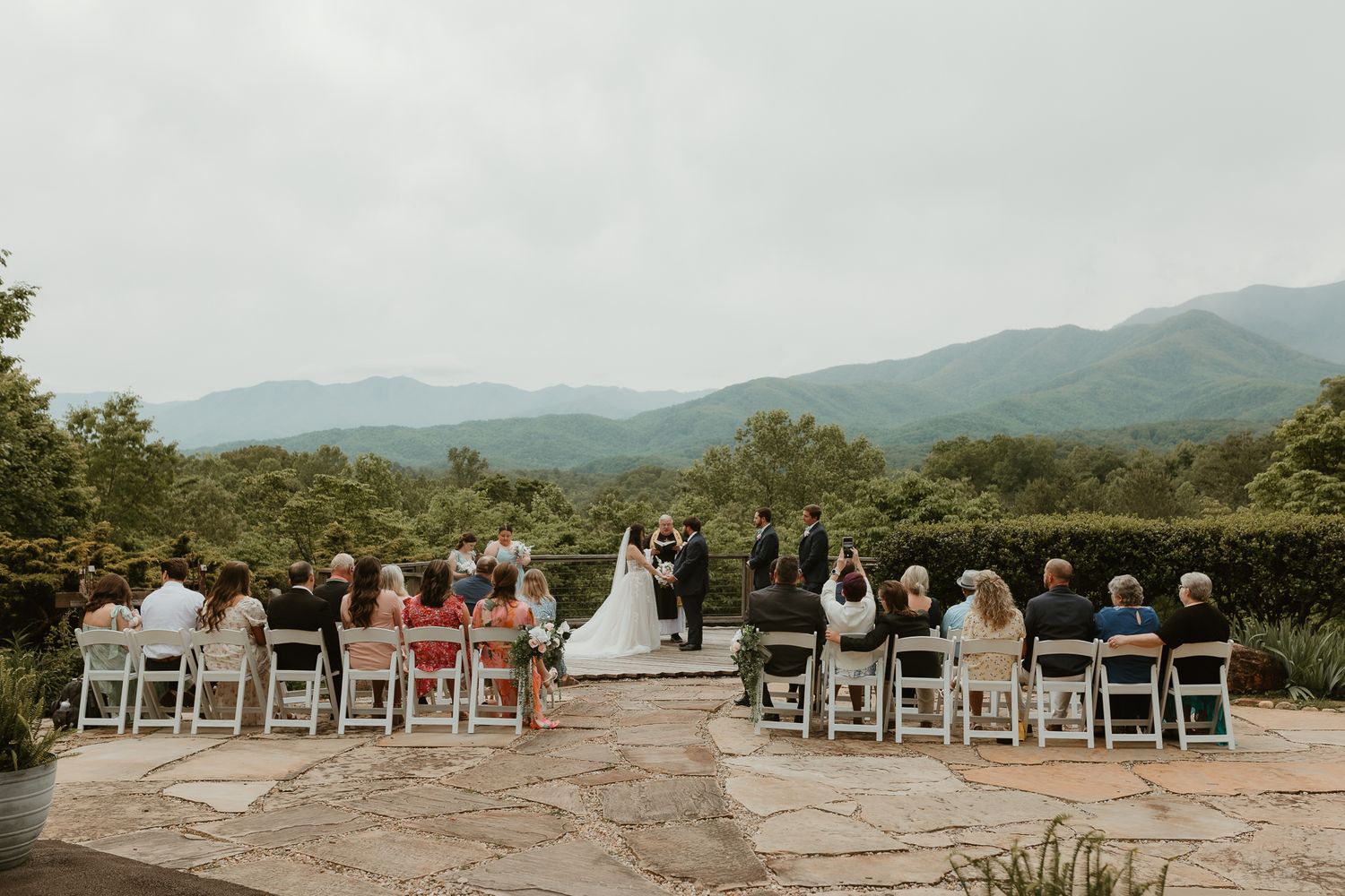 Mountain wedding ceremony setup with white chairs overlooking scenic valley vista.
