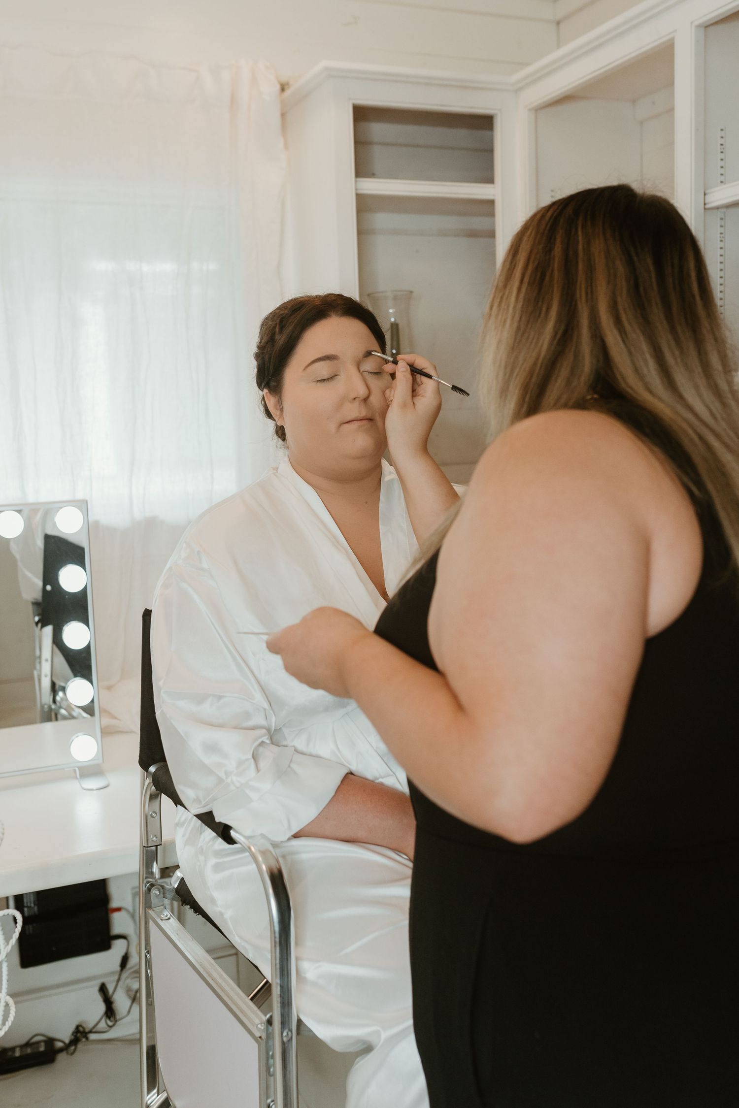 Wedding day makeup preparation session in a bright dressing room.