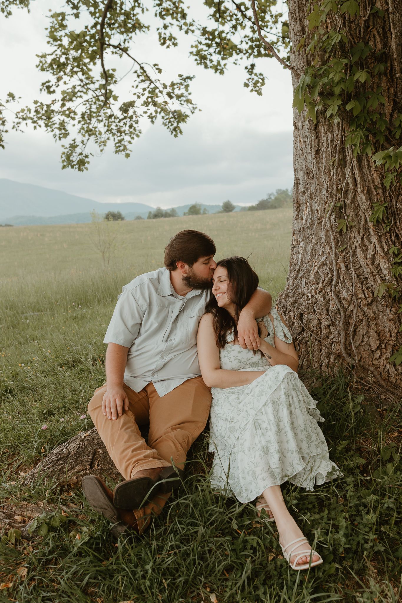 Romantic couple photos under a large tree in a mountain meadow.