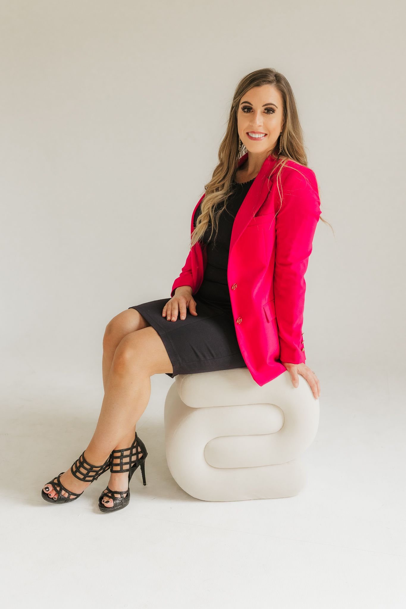 Fashion portraits with black dress and hot pink blazer against white backdrop.