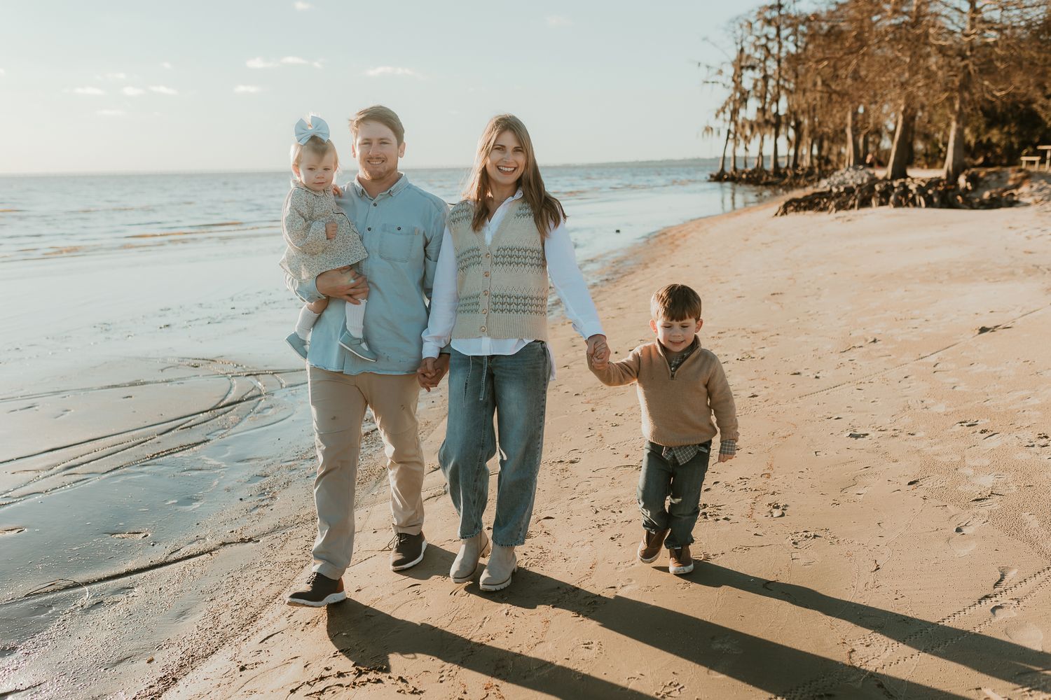Family walking together along a scenic beach shoreline at sunset.