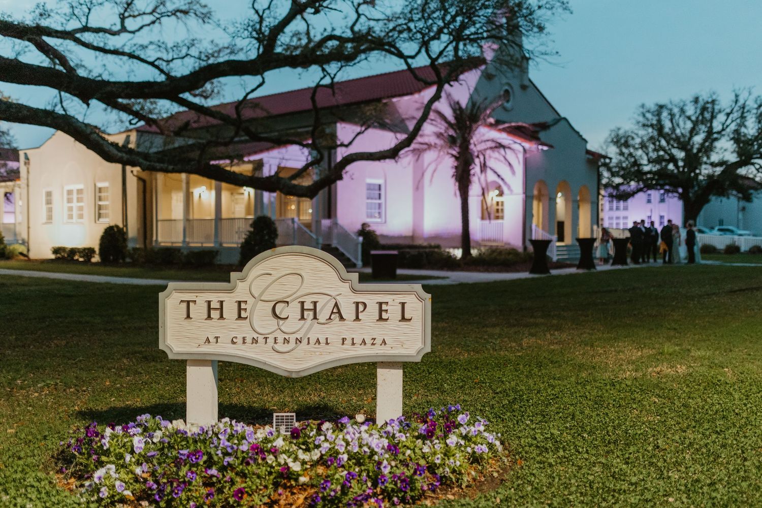 Illuminated chapel venue at night with sign and landscaping in foreground.