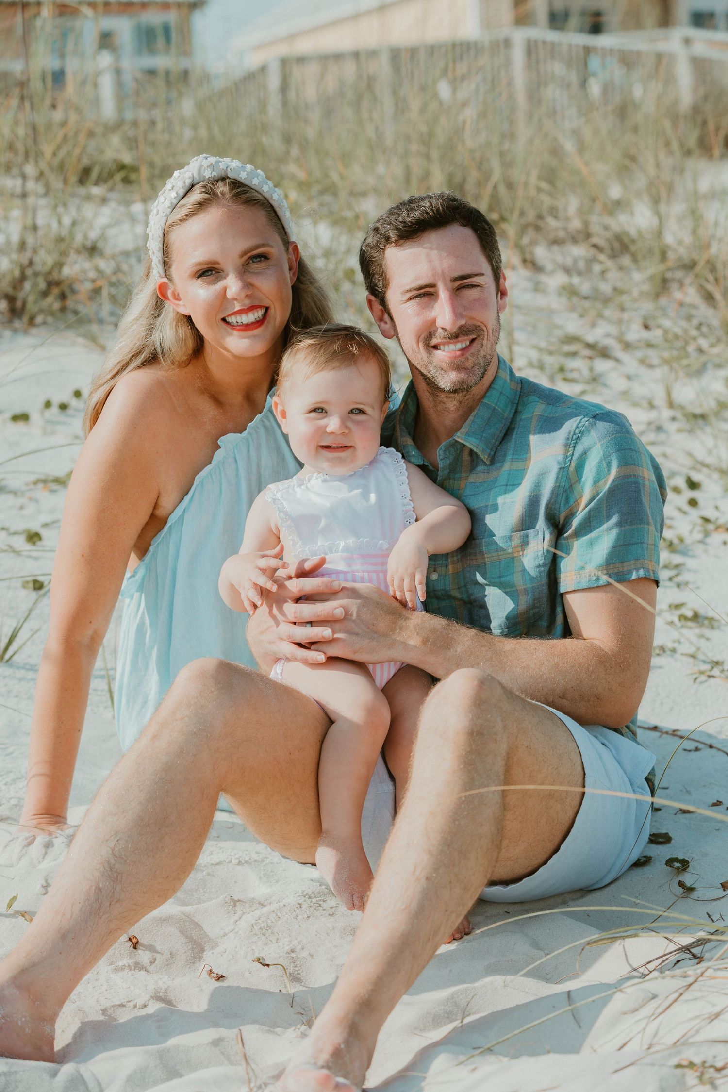 A casual beach photo session with people sitting together on white sand.