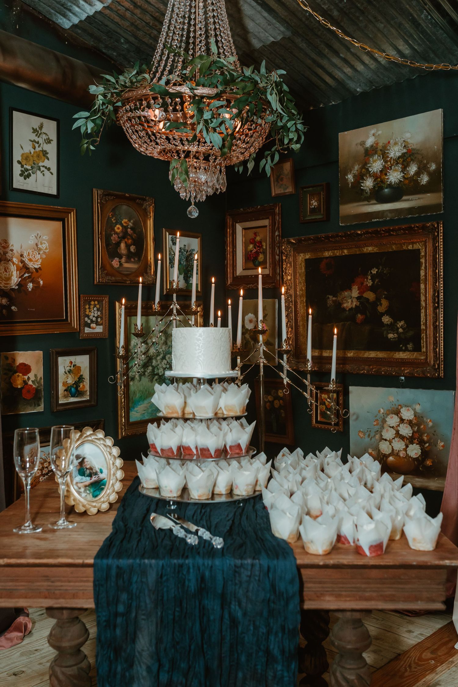 Elegant dessert display with white treats and candelabras under crystal chandeliers.