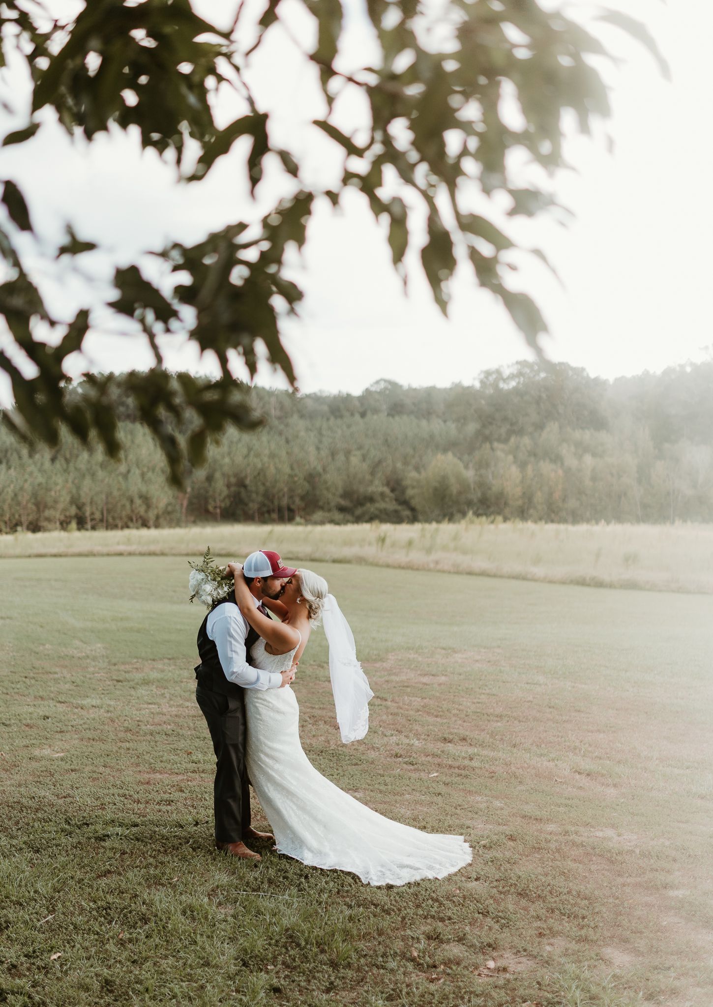 Wedding couple sharing intimate moments in an open field during sunset.