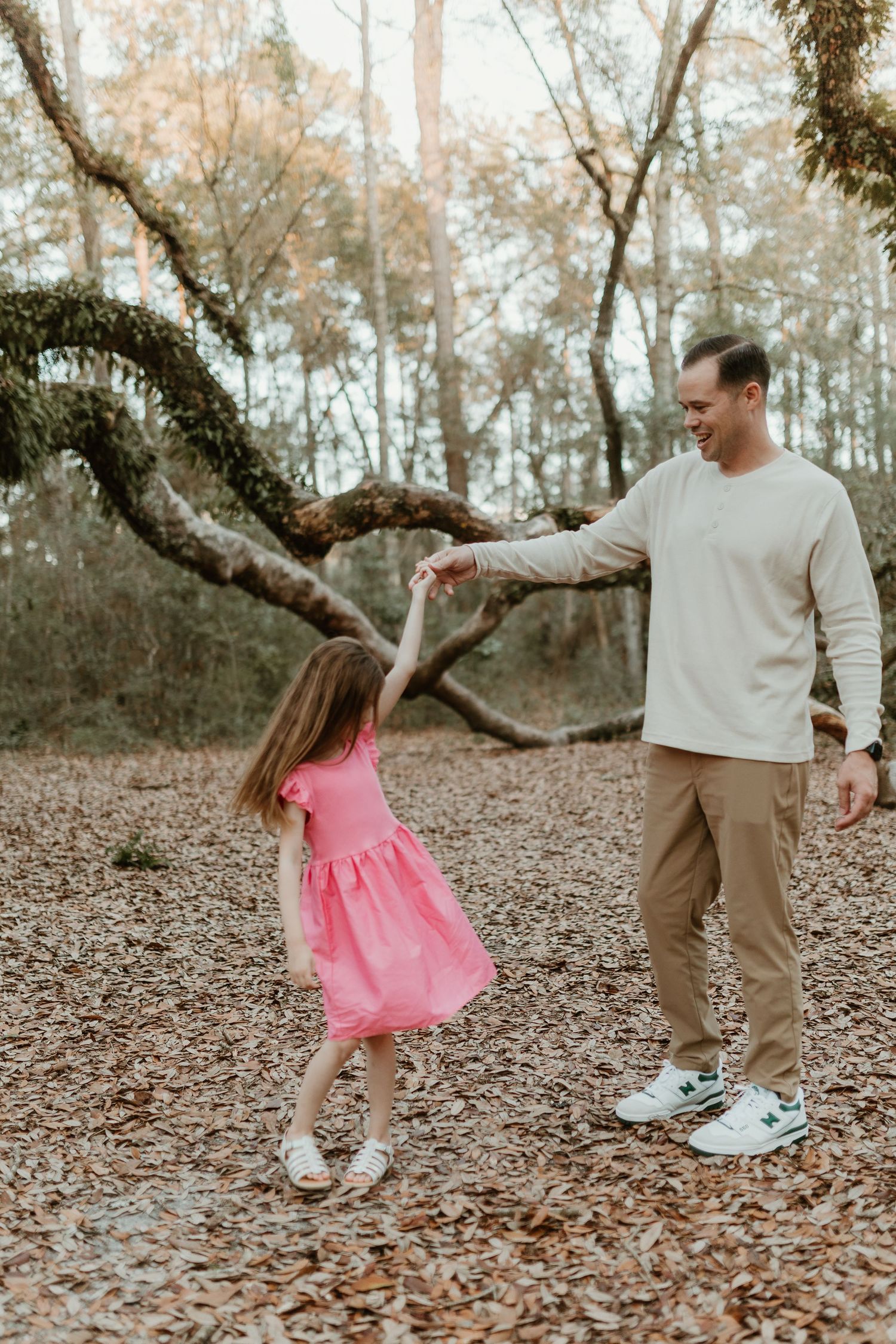 A playful dance scene in a wooded area with pink dress twirling against autumn leaves.