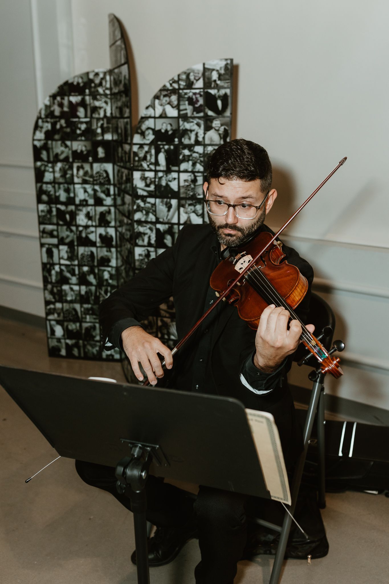 Violinist in black attire performs at an event with sheet music stand.