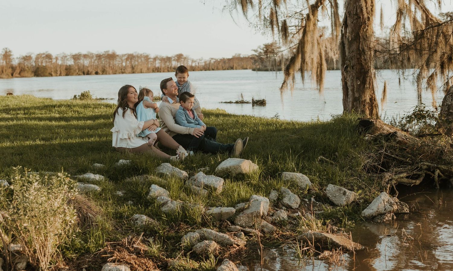 Scenic lakeside wedding venue with Spanish moss hanging from trees at sunset.