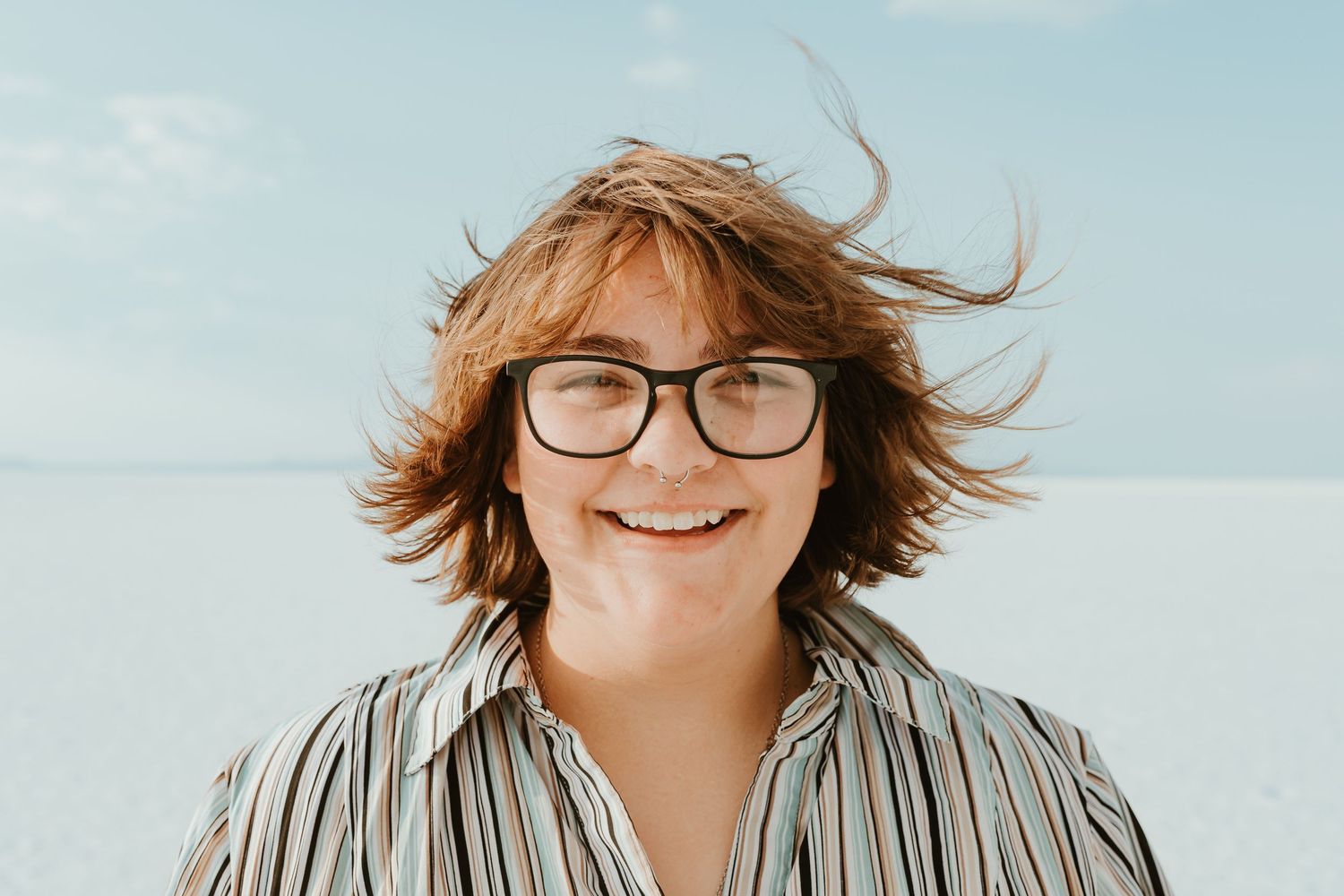 Candid portraits on white salt flats with mountains and blue sky in background.