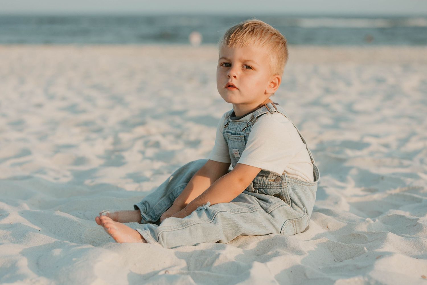 Child playing in pristine white sand during a beach photoshoot.