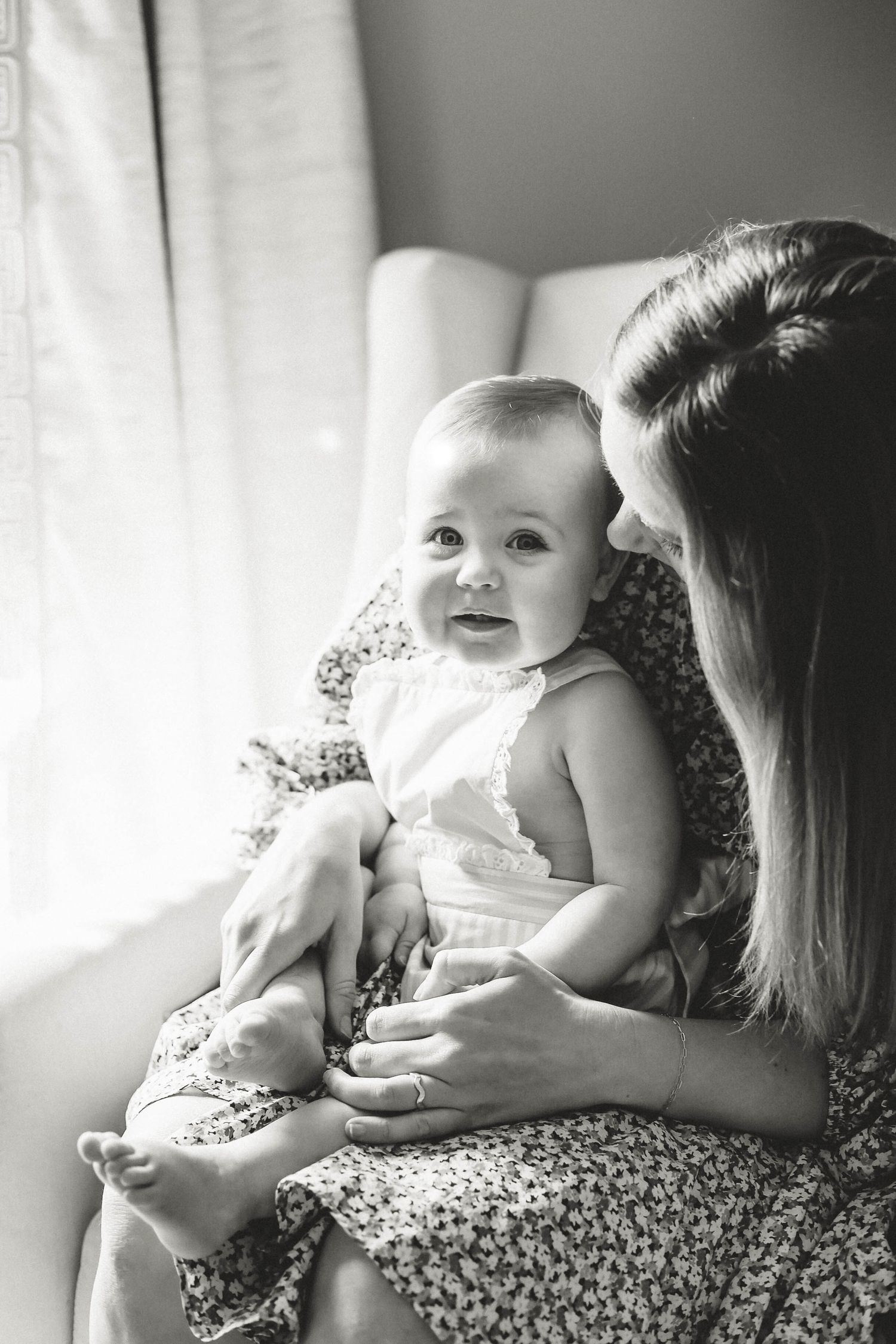 Sweet black and white portrait series of a baby being held on floral bedding.