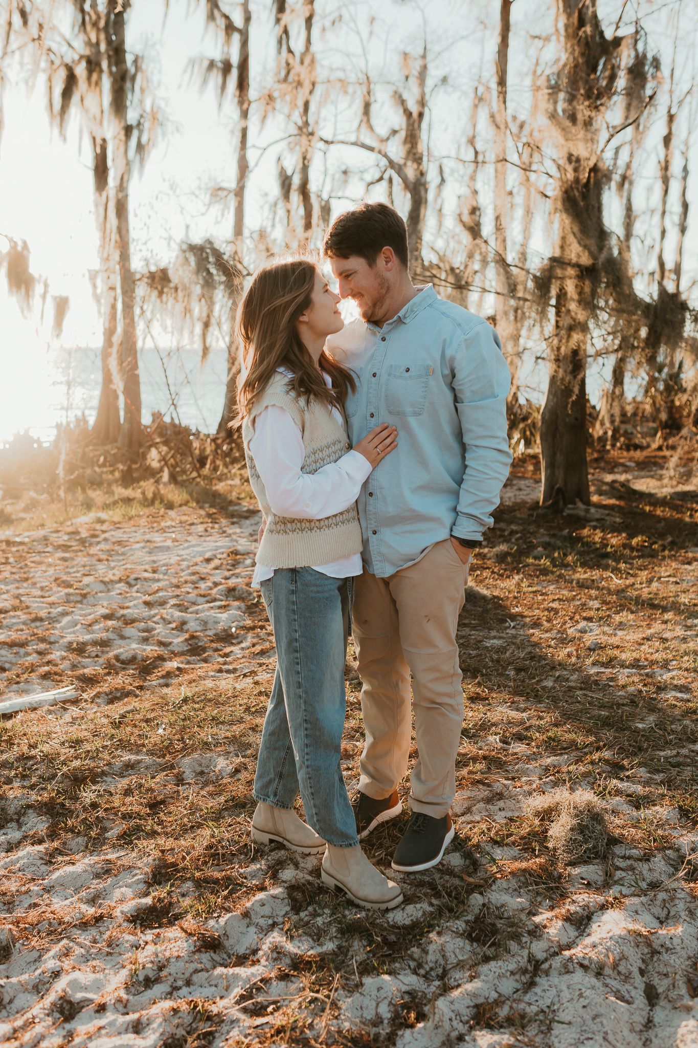 Romantic couple sharing an intimate moment in a sunlit wooded area.