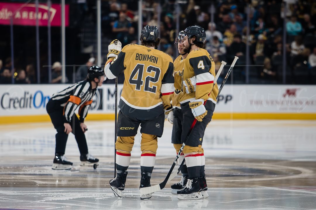 Hockey players in gold and white uniforms compete during an NHL game.