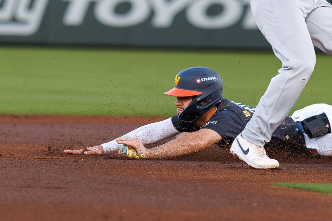 Baseball player slides headfirst into base during a game.