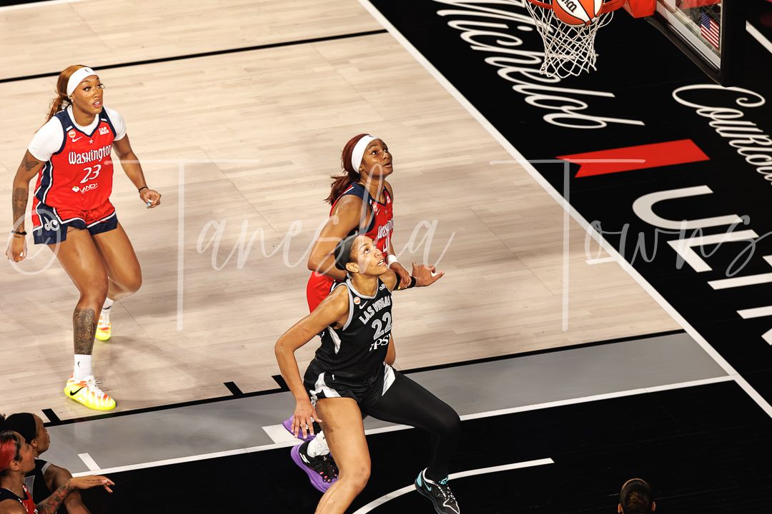 WNBA players in action during a basketball game, with one player driving to the basket for a layup.