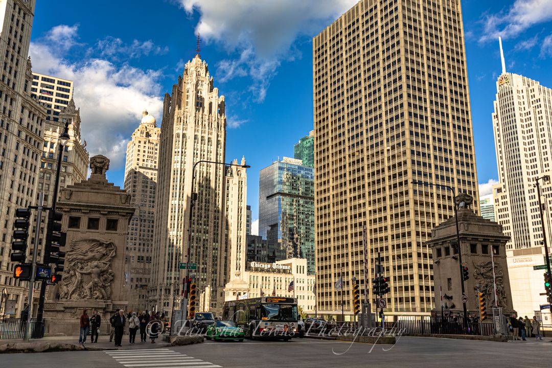 Historic Chicago architecture and skyscrapers line Michigan Avenue on a sunny day with white puffy clouds.