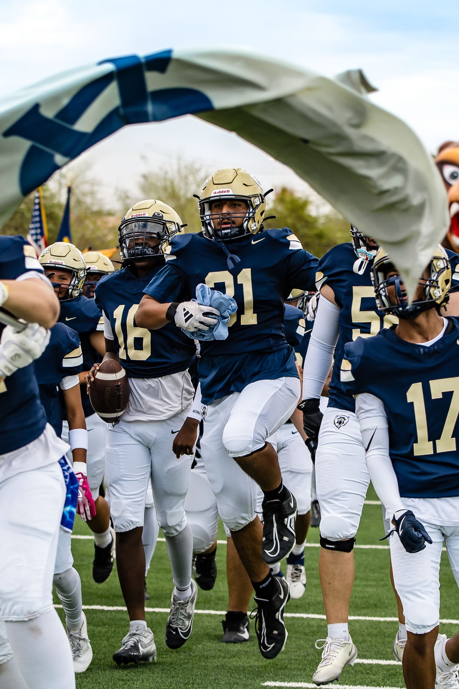 Football team in navy and white uniforms running together on the field.