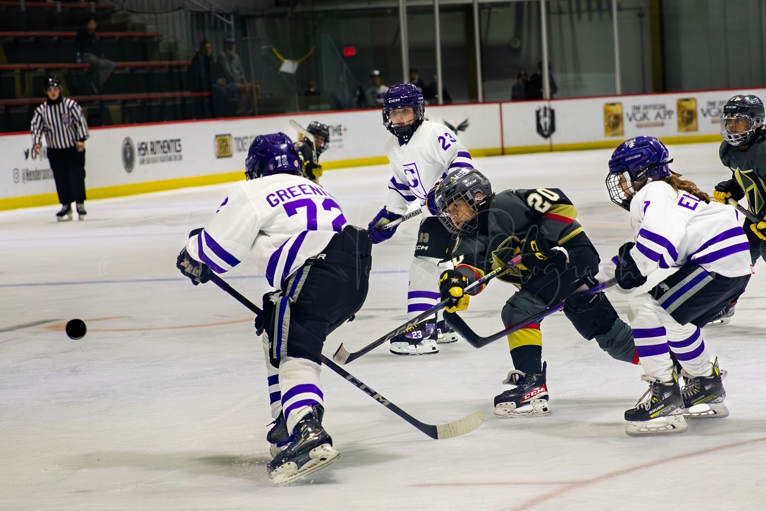 Hockey players from opposing teams battle for puck control during face-off.