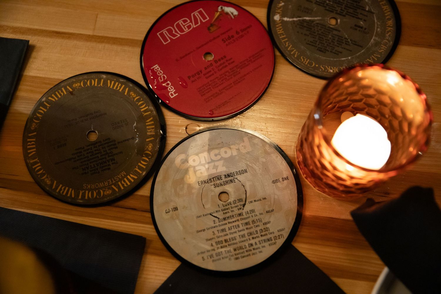Collection of vintage vinyl records arranged on a wooden surface with warm lighting.