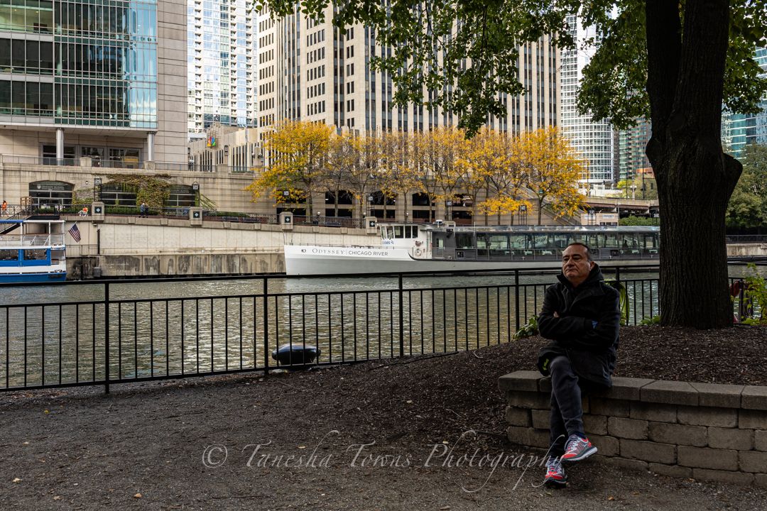 Urban skateboarder performs trick on concrete ledge in front of modern city buildings during autumn.