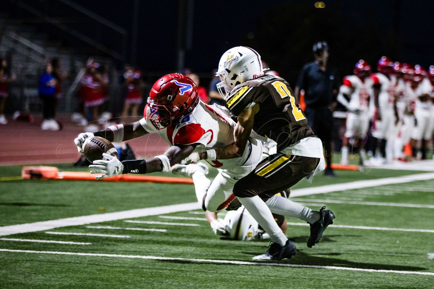 Football players from opposing teams collide during an intense nighttime play.