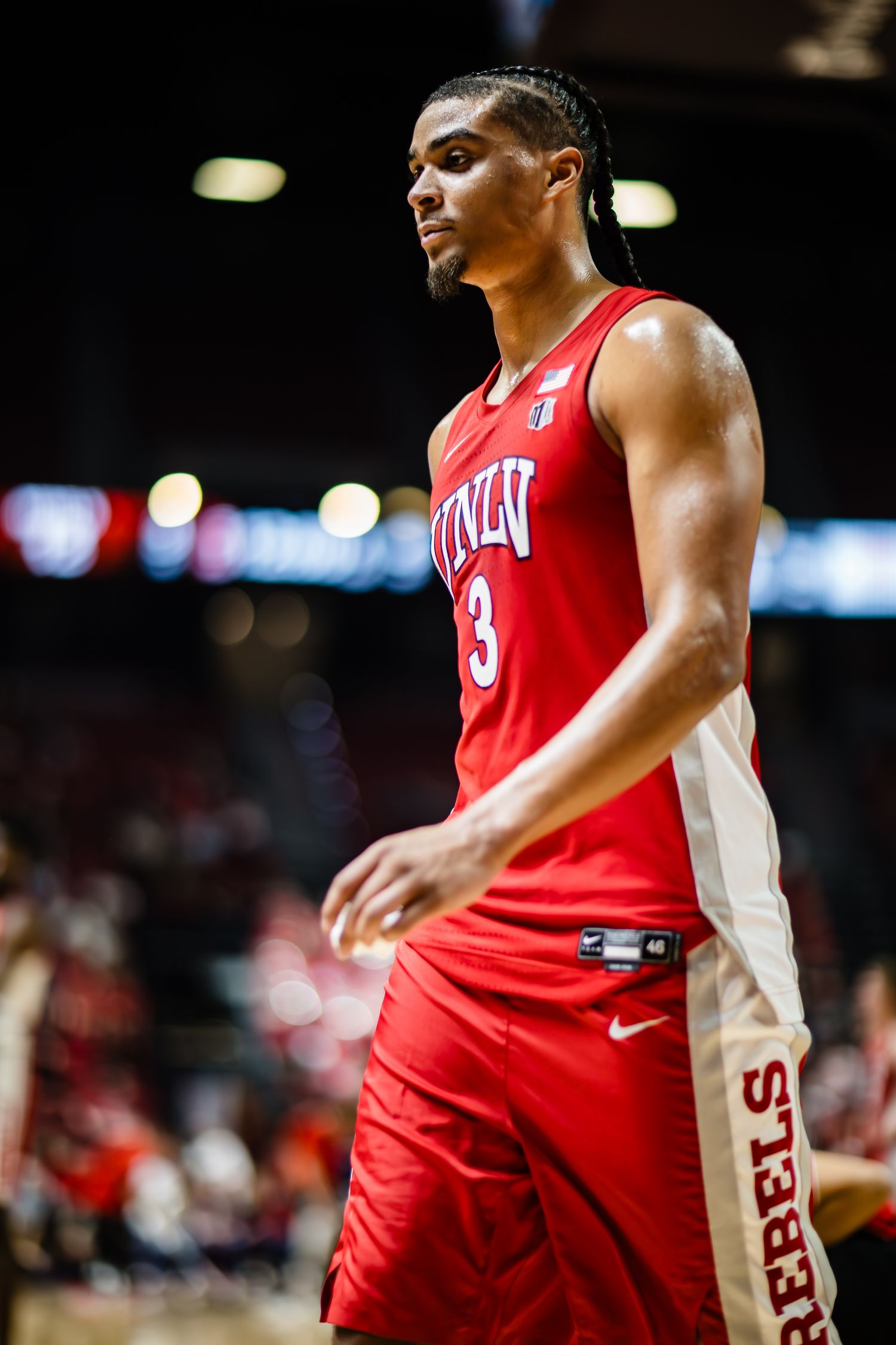 UNLV Rebels basketball player wearing red jersey number 3 stands on the court during a college basketball game.