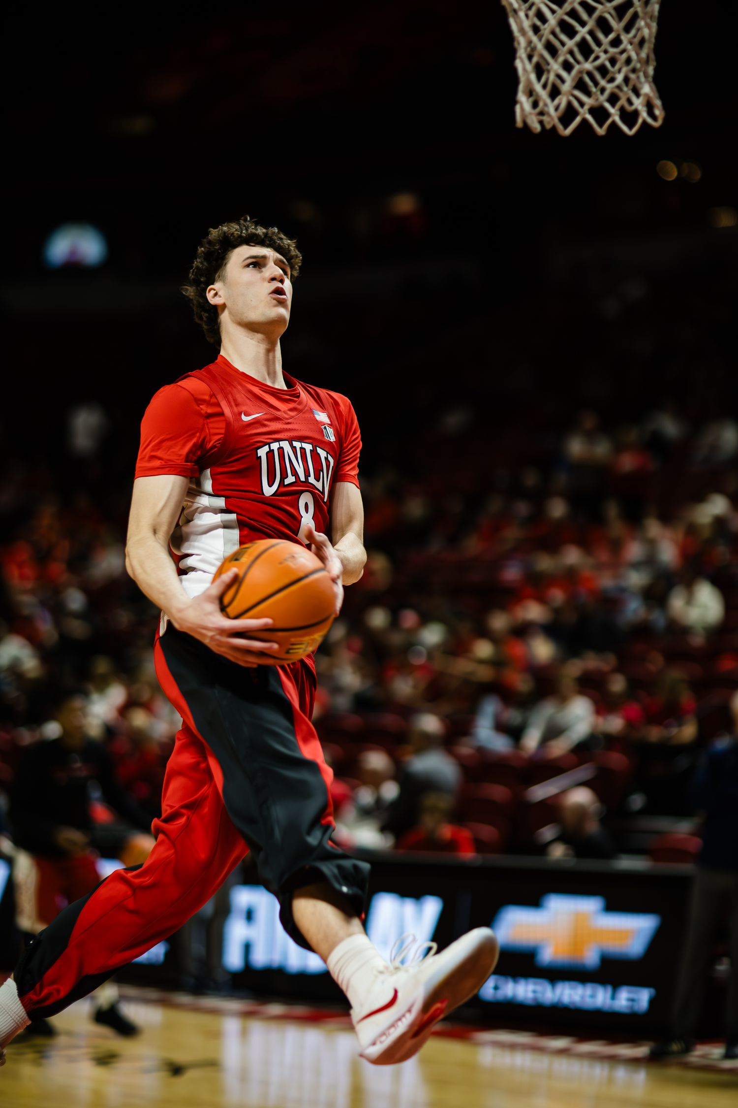UNLV Runnin' Rebels player #8 drives to the basket during a college basketball game at a packed arena.