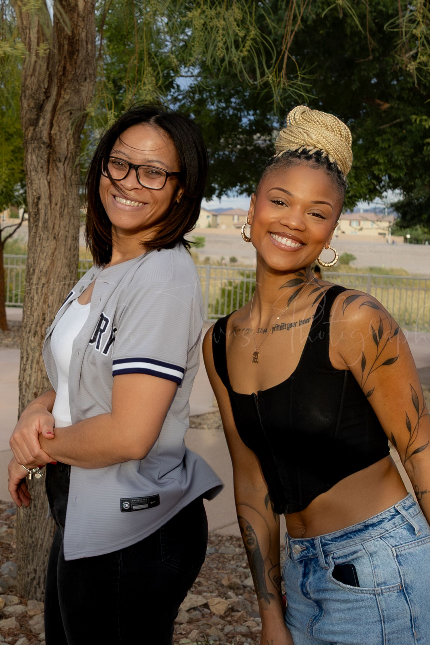 Friends posing and laughing together near trees at outdoor event.