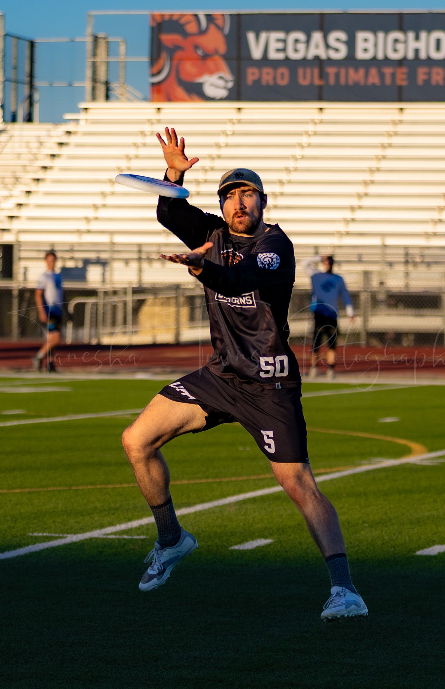 Athletes practicing coordinated movements on a sports field with stadium bleachers in the background.