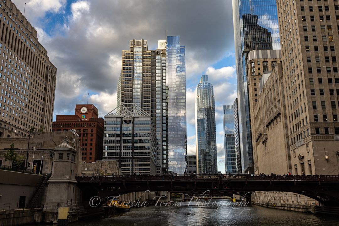 Panoramic cityscape view of Chicago's iconic architecture and DuSable Bridge over the Chicago River on a cloudy day.
