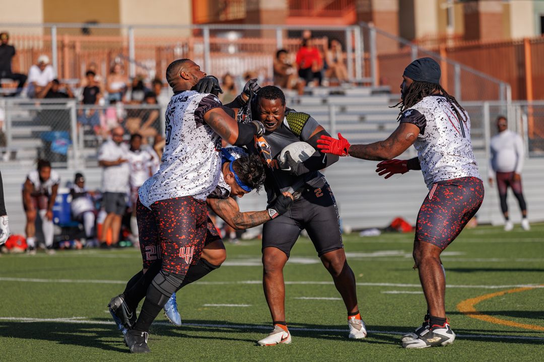 Athletes battle for the ball during a competitive flag football game on a green turf field.