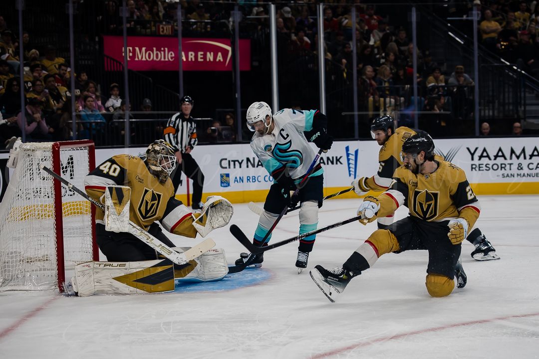 A Sharks player attempts to score while Golden Knights defenders protect their goal.
