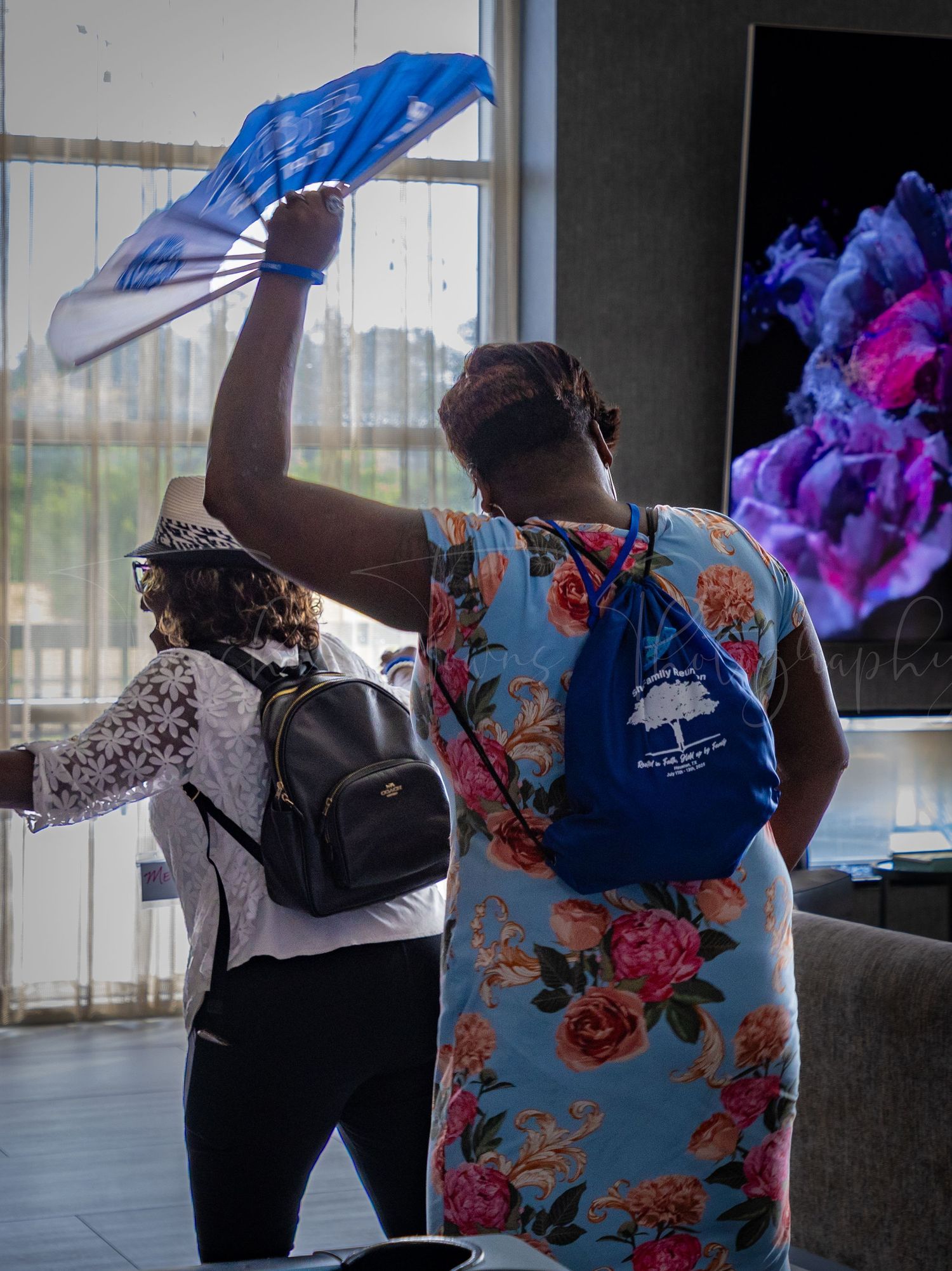 People in colorful floral outfits standing by windows with blue lighting effects.