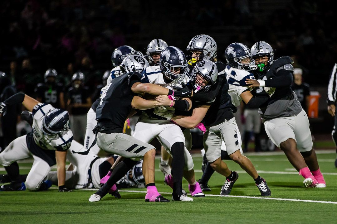 Players from opposing teams crouch in pre-snap formation on the football field.