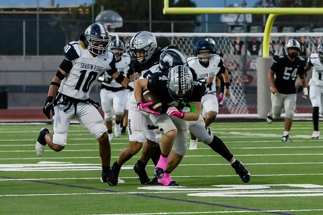 Football players line up at the line of scrimmage during an evening game under stadium lights.