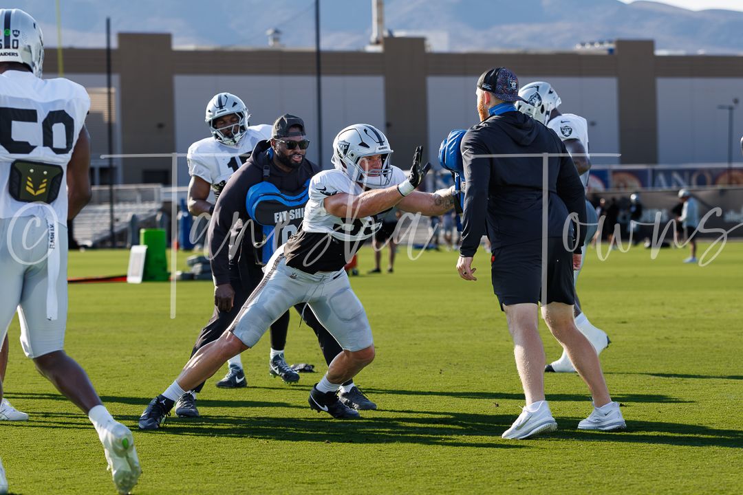 Las Vegas Raiders players engage in blocking drills during outdoor training camp practice.