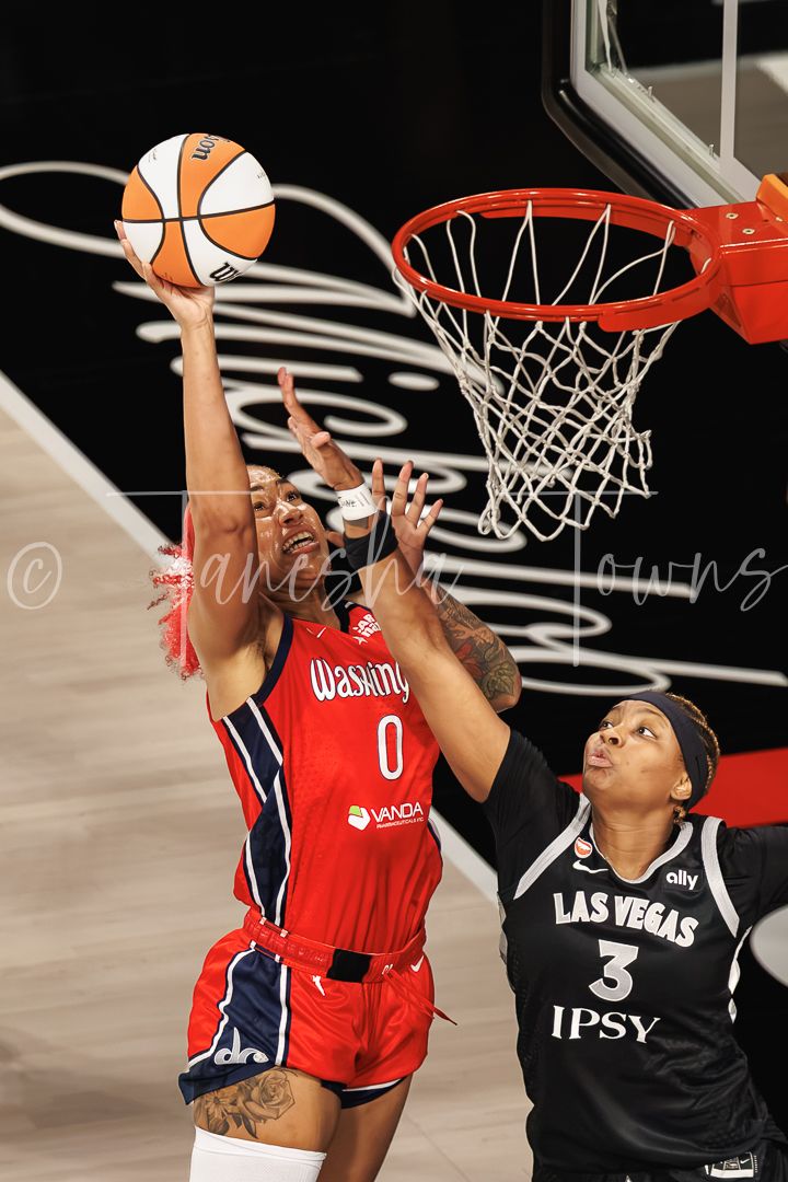 Washington Mystics player #0 attempts a layup against Las Vegas Aces #3 in a WNBA game.