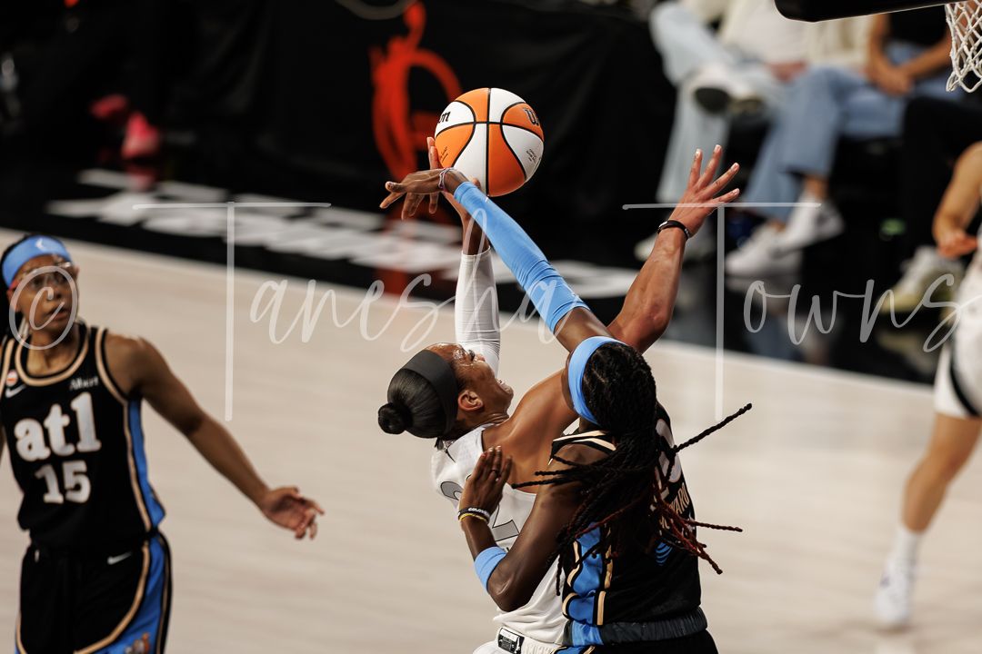 WNBA player drives to the basket against Atlanta Dream defenders during an intense women's basketball game.