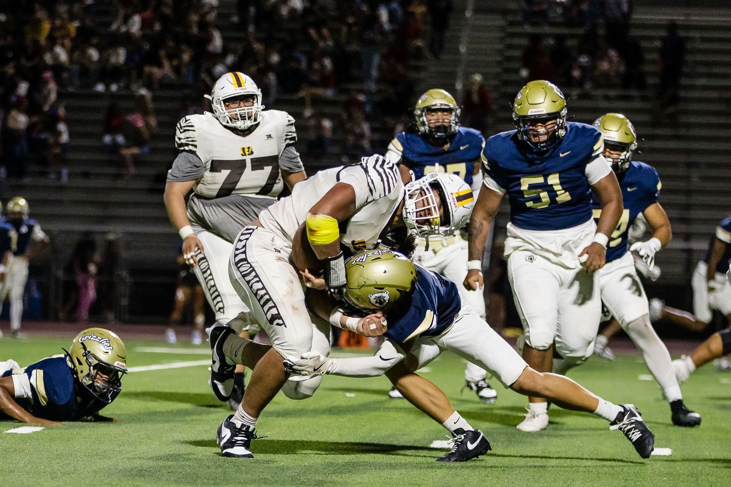 Football players lined up in formation during a nighttime game.