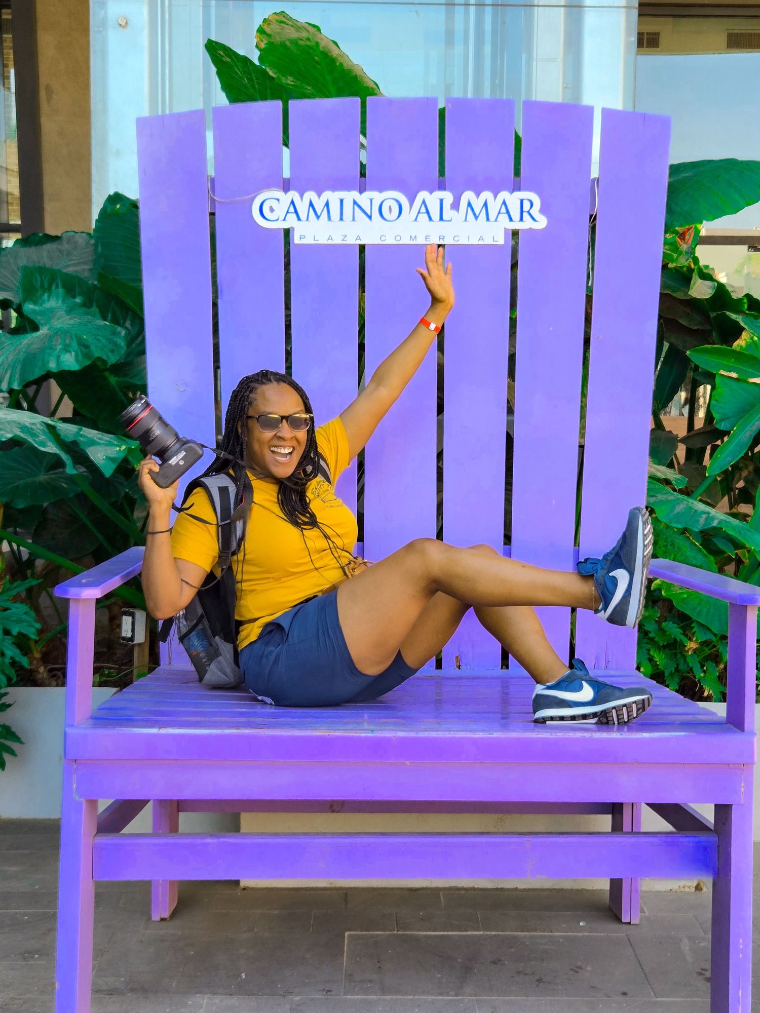 Playful sequence of someone in a yellow shirt posing and lounging on a large purple outdoor bench.