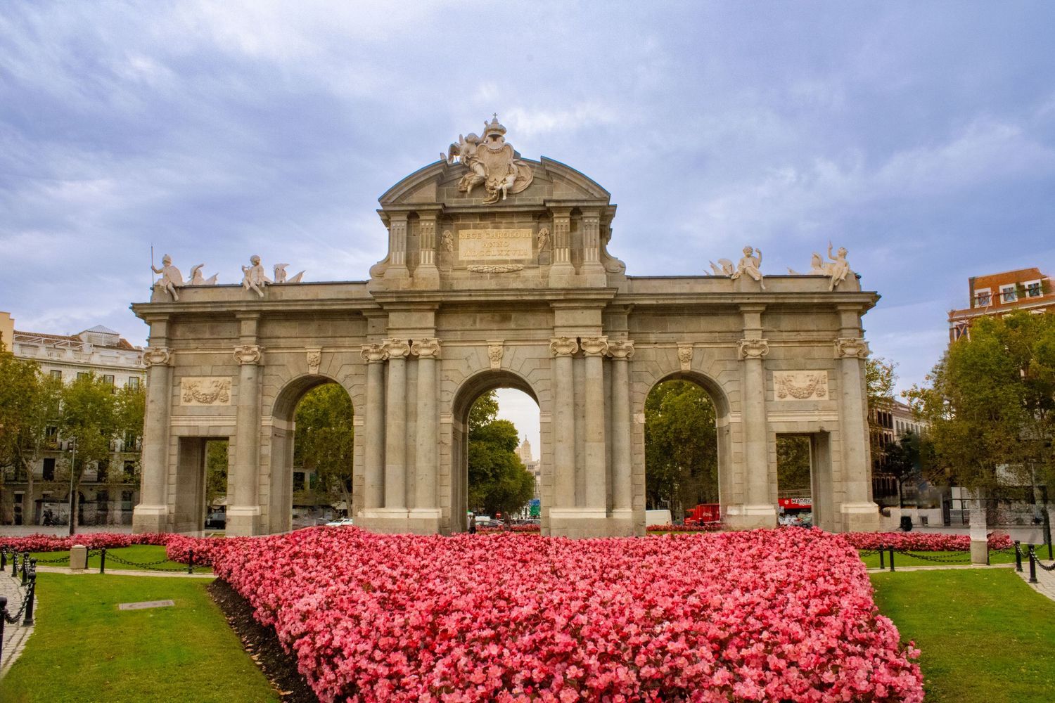 Panoramic view of a historic stone monument with vibrant red tulips blooming in the foreground.